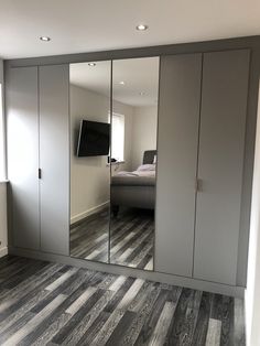 an empty bedroom with mirrored closet doors in the middle and a bed on the other side