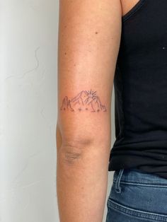 a woman with a tattoo on her arm that has mountains and stars in the sky