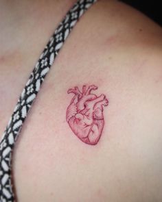 a small heart tattoo on the back of a woman's shoulder