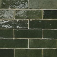 a green brick wall with water running down it's side and the bottom part of the wall