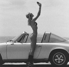 a woman standing on top of a white car