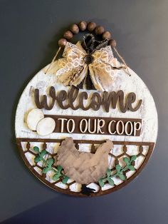 a welcome sign hanging from the side of a wall next to a wooden plaque that says welcome to our coop