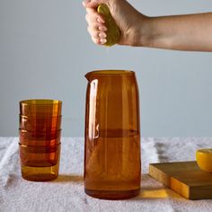 a person is pouring orange juice into a pitcher