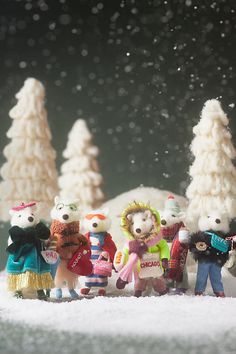 a group of toy animals standing next to each other in front of snow covered trees