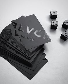 a stack of black and white business cards sitting on top of each other next to dice