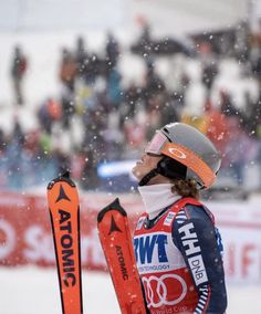 a woman standing on top of a snow covered slope holding skis