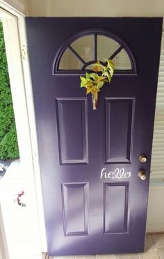 a purple door with the word hello written on it and a yellow flower in front