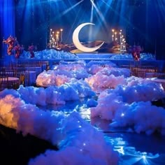 a stage set up for a wedding with clouds on the ground and lights shining down