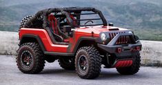 a red and black jeep parked on top of a hill