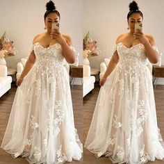 a woman taking a selfie while wearing a wedding dress with flowers on the skirt