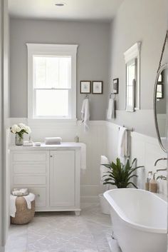 a white bathroom with a tub, sink and window in it's center area