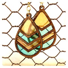 two stained glass earrings hanging from a chain link fence