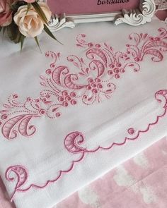 a pink and white table cloth with some flowers on top of it next to a frame