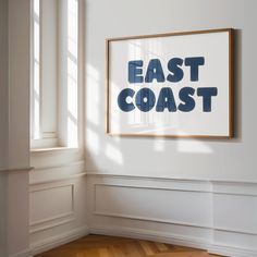 an east coast poster hanging on the wall in a white room with wood flooring