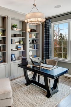 a home office with built - in bookcases and a chandelier