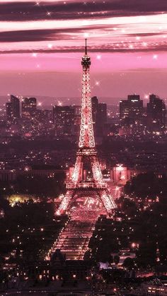 the eiffel tower lit up in pink and purple at night with city lights