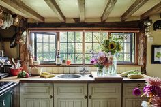 a kitchen with sunflowers and other flowers on the window sill above the sink