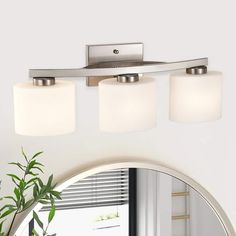 a bathroom vanity light with three lights and a round mirror in front of the sink