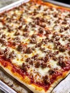 a pizza sitting on top of a metal pan covered in cheese and meat toppings