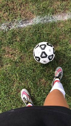 a person standing next to a soccer ball on top of a green grass covered field