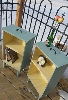 two side tables with books and magazines on them in front of a black iron fence