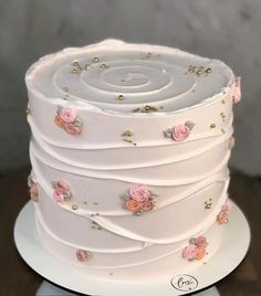 a white wedding cake with pink roses on the top and gold sprinkles