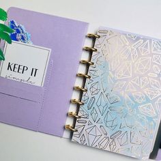 an open planner book on top of a desk with a plant in the corner next to it