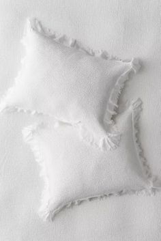 two white pillows with ruffled edges on a bed