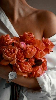 a woman holding a bouquet of flowers in her hands and wearing a white shirt with buttons on it