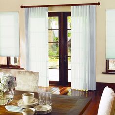 the dining room table is set for two with place settings and flowers in vases