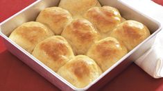 a casserole dish with rolls in it on a red table