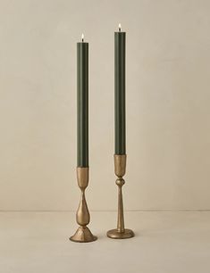 two candles are standing next to each other on a white surface with one candle in the middle