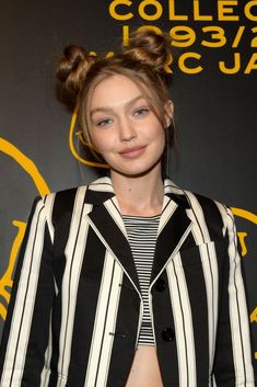 a young woman wearing a black and white striped shirt with her hair in a high bun