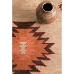 a vase sitting on top of a wooden table next to a rug