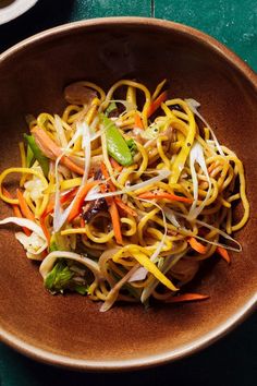 a brown bowl filled with noodles and vegetables