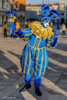 a man dressed in blue and gold is standing on the street