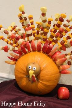 a turkey made out of candy sticks sitting on top of a table next to an apple