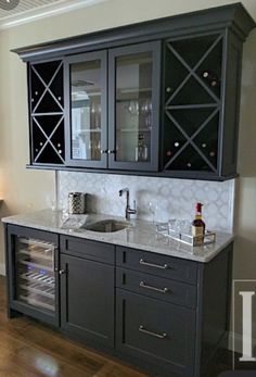 a kitchen with black cabinets and marble counter tops in the middle of wood flooring