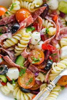 a pasta salad with tomatoes, olives, cucumbers and ham