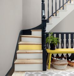 the stairs are painted yellow and white with black balconies on each side, along with potted plants