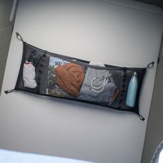 a hanging storage bag filled with items on top of a white wall next to a window