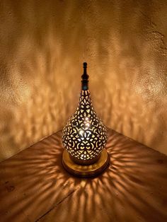 a lamp that is sitting on top of a wooden table next to a brown wall