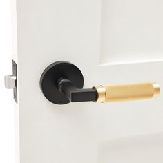 an open door with a black handle and gold bar on the handle, in front of a white wall