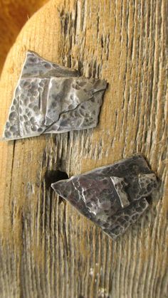 two pieces of metal sitting on top of a wooden door handle with holes in it