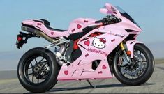 a pink hello kitty motorcycle parked on the side of the road with hearts painted on it