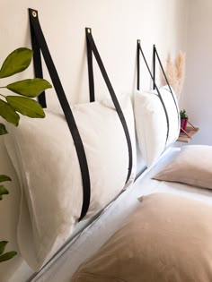 three white pillows hanging on the wall next to each other with black straps attached to them