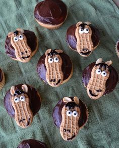 there are many cookies with chocolate frosting on the green table cloth and one has an image of a horse