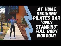 a woman standing on top of a sidewalk next to a tall building with the words at home beginner plates bar only standing full body workout