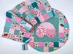 a patchwork table mat with an elephant design on it and two rolls of thread next to it