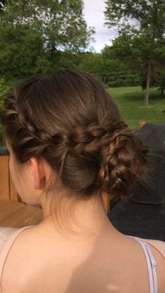 a woman with braids in her hair sitting on a bench looking at the park